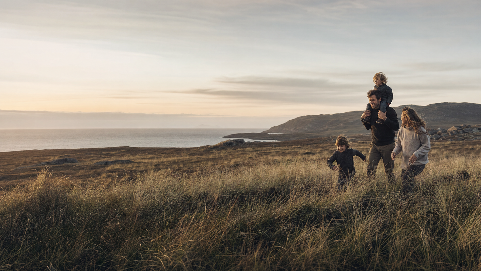 A family walking through coastal grassland at golden hour
